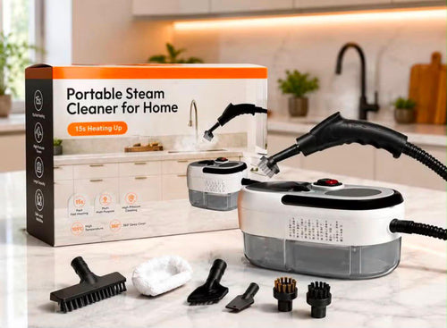 Portable steam cleaner set displayed on a kitchen countertop with its retail box, handheld wand, hose, and multiple cleaning attachments. The box reads 'Portable Steam Cleaner for Home' and '15L Heating Up.
